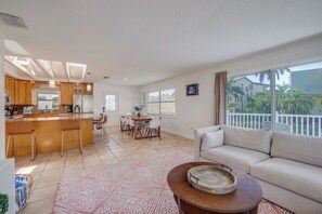 A modern living room with a sofa, a coffee table, and a dining area with chairs and a table. - Bean Point Residence Unit A (Anna Maria)