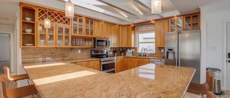 A modern kitchen with granite countertops, stainless steel appliances, and wooden cabinetry.