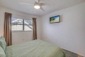A bedroom with a bed, a ceiling fan, a window with curtains, and a wall-mounted TV. - Bean Point Residence Unit A (Anna Maria)