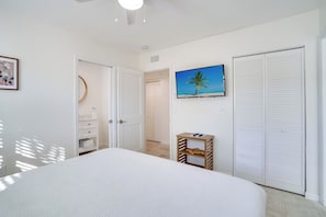 A bedroom with a bed, a TV, a wardrobe, and a door leading to another room. - Bean Point Residence Unit B (Anna Maria)