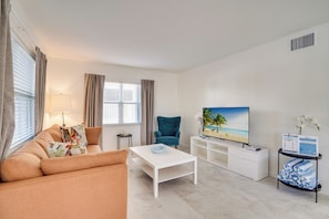 A modern living room with a sofa, coffee table, TV, and a small side table. - Bean Point Residence Unit B (Anna Maria)