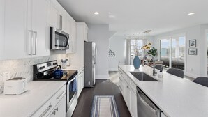 A modern kitchen with white cabinetry, stainless steel appliances, and a large island with a sink.