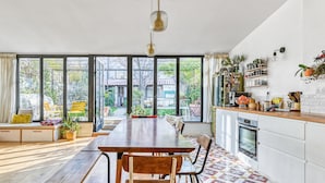 Una cocina amplia con una gran mesa de comedor, sillas de madera y piso de baldosas.