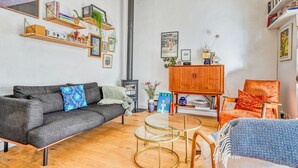 Una sala de estar con sofá, sillones, una mesita de centro, una estantería y una chimenea.