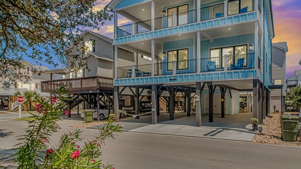 A multi-story waterfront property with a balcony on the second floor, a covered parking area, and a stop sign in the foreground. - New Beautiful Home @ Ocean Lakes Family  Campground! BE THE FIRST TO RENT! (Myrtle Beach)