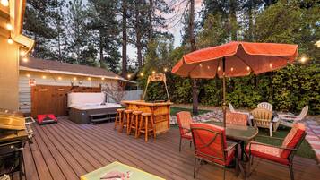 Eine Terrasse mit Gartenmöbeln, einem Whirlpool und Lichterketten.