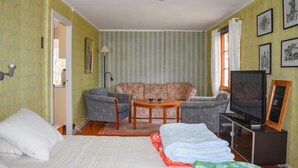 Une pièce comprenant un lit, deux canapés, une petite table, un téléviseur et des tableaux encadrés accrochés au mur.