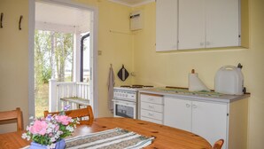 Une cuisine avec des meubles blancs, une cuisinière et un évier. On y trouve une table à manger avec des chaises et un vase rempli de fleurs.
