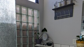 Una cucina con una finestra, uno scaffale con piante, un cesto con utensili da cucina e un contenitore di semi di girasole.