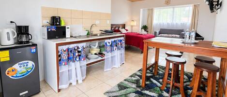 Una habitación de hotel compacta con kitchenette, zona de comedor y cama.
