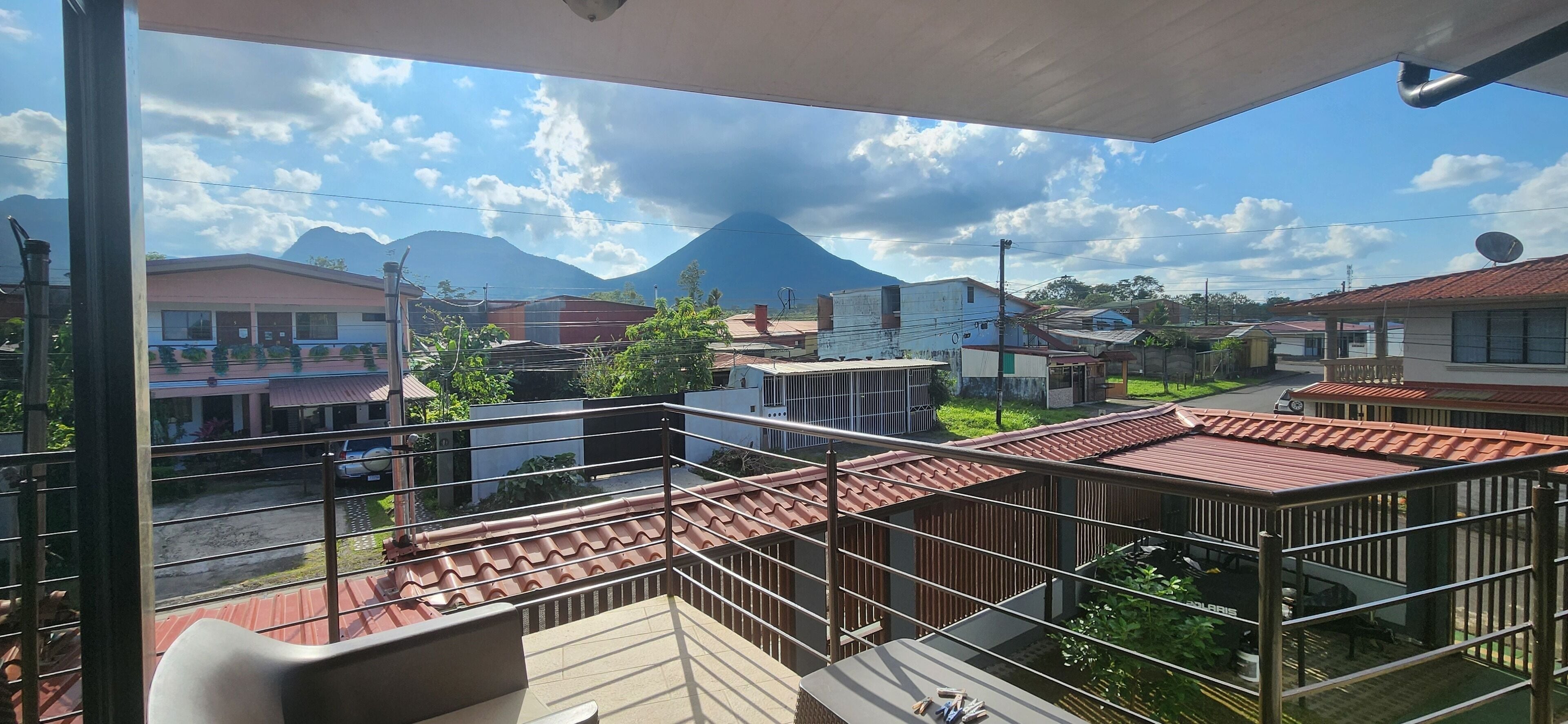 A balcony with a view of a mountain, buildings, and a clear sky.