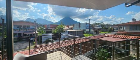 A balcony with a view of a mountain, buildings, and a clear sky.