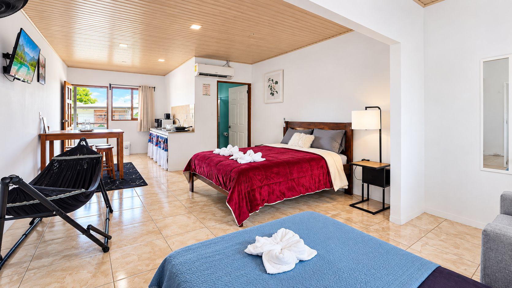 Habitación de hotel con cama, escritorio, silla, alfombra azul y vistas al exterior.