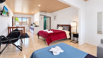 Habitación de hotel con cama, escritorio, silla, alfombra azul y vistas al exterior.