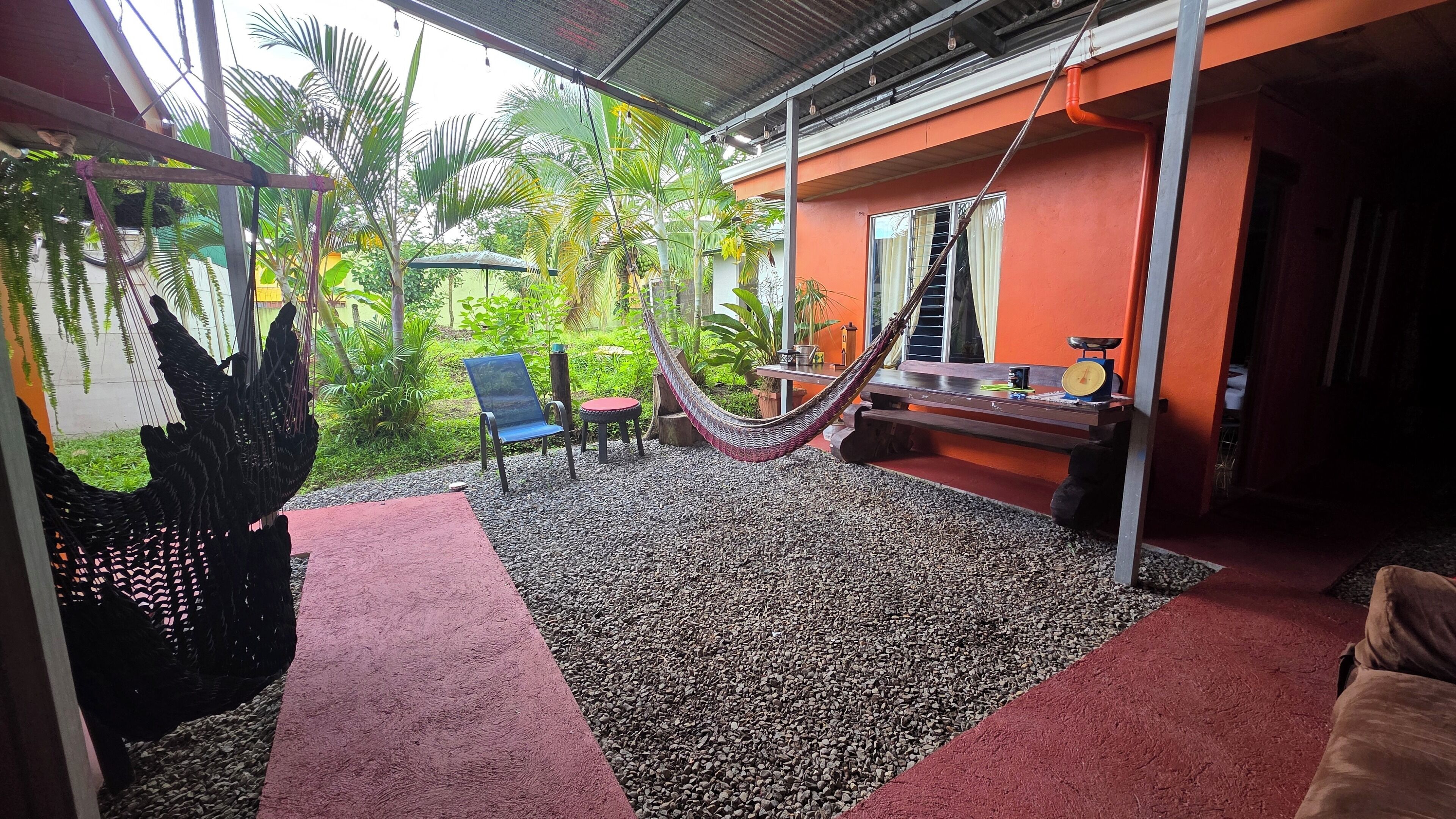 A covered outdoor area with a hammock, seating, and a small table.