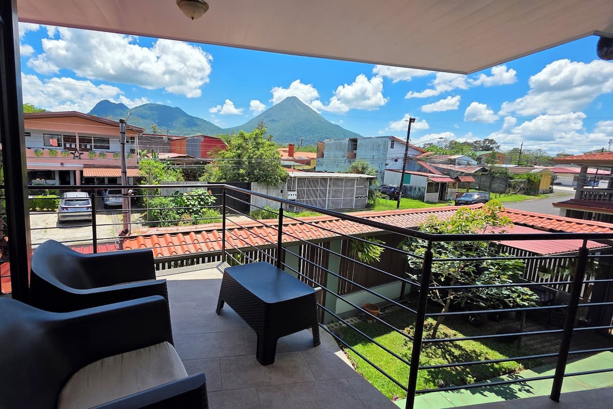 A balcony with a view of a mountain, a car, and buildings.