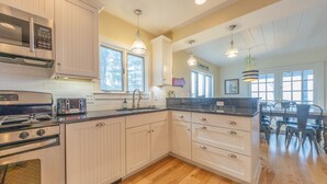 A kitchen with white cabinetry, a stainless steel range, and a wooden floor.