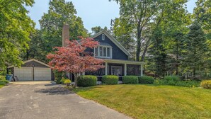 A two-story house with a garage, a covered porch, and a well-maintained lawn.