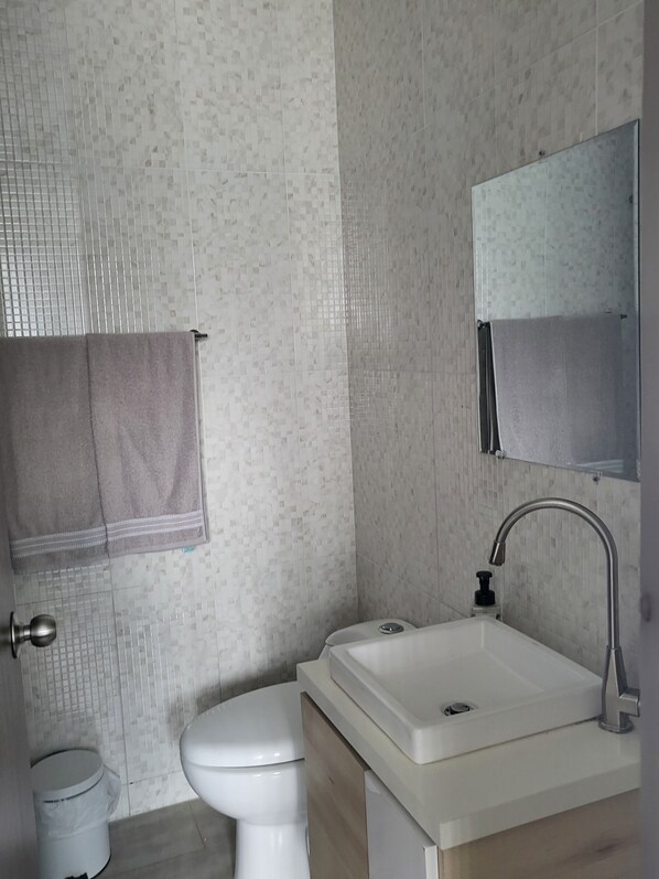 Une salle de bain avec des toilettes, un lavabo et un miroir.
