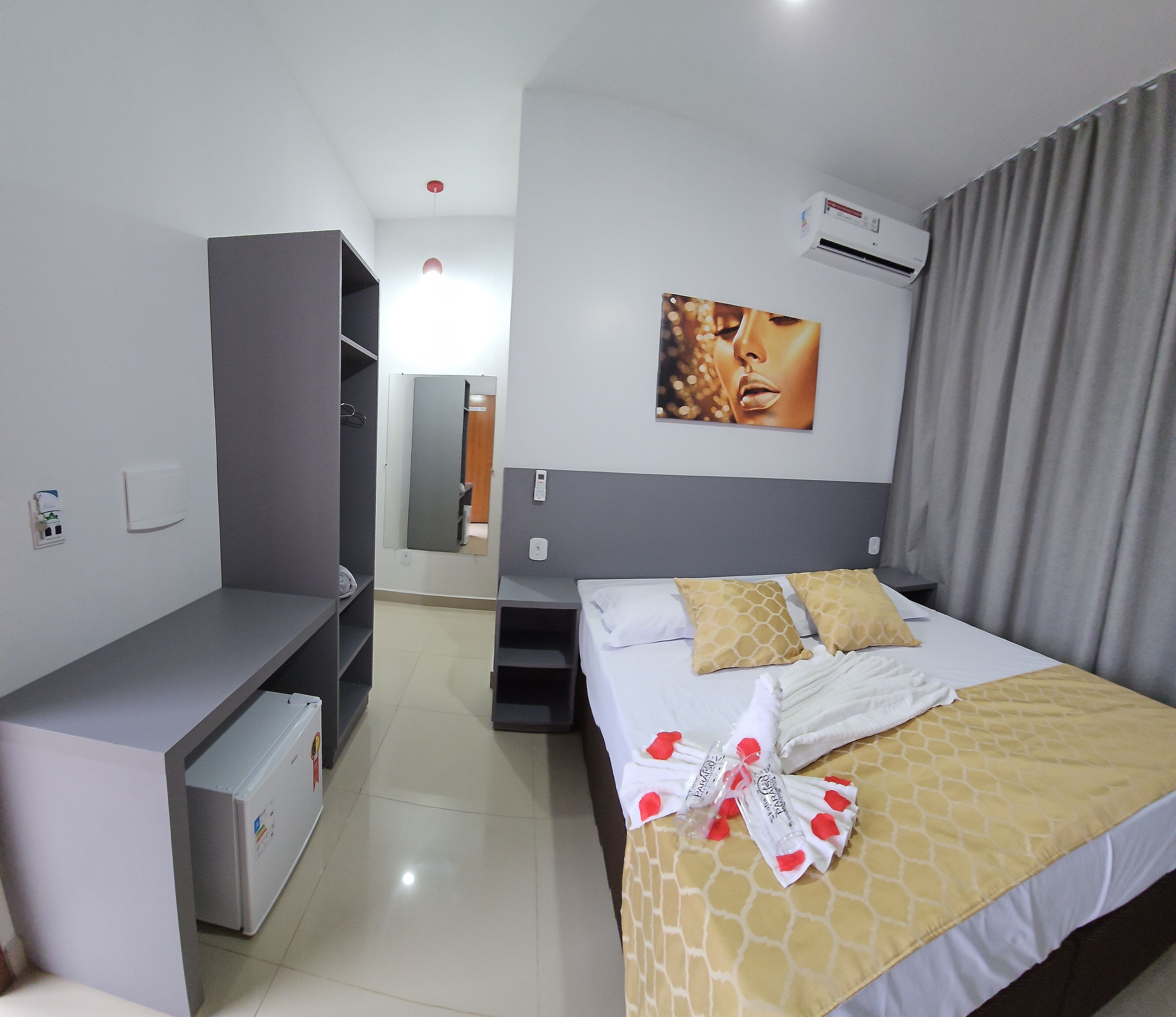 Habitación de hotel con cama, escritorio, armario y unidad de aire acondicionado.