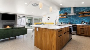 Una cocina moderna con una isla central, armarios de madera y un salpicadero azul.