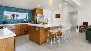 Una cocina moderna con una isla grande, armarios de madera y un salpicadero azul.