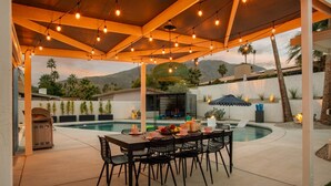 Un patio al aire libre con piscina, zona de estar cubierta y una mesa de comedor preparada para cuatro.