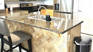 A kitchen with granite countertops, a stainless steel refrigerator, and wooden cabinets. - Beautiful ocean view and beach front close to shopping downtown  (Panama City Beach)