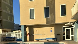 A swimming pool with a '5 FT. NO DIVING' sign, a blue bench, and a building with multiple windows and a door. - Beautiful ocean view and beach front close to shopping downtown  (Panama City Beach)