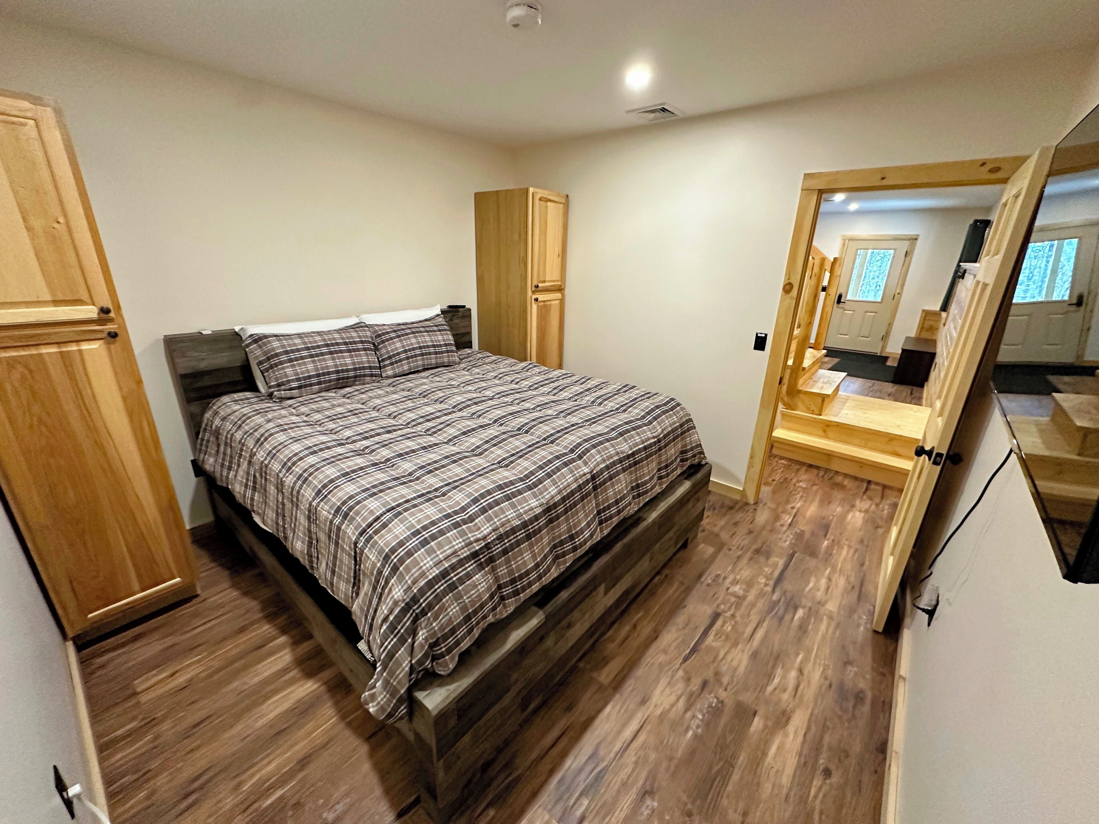 A bedroom with a bed, wooden wardrobe, and a wooden bench.