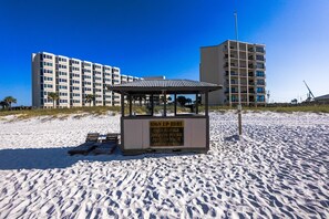 Un quiosco en la playa con un cartel publicando alquiler de sillas, tours para ver delfines y paseos en pontones.