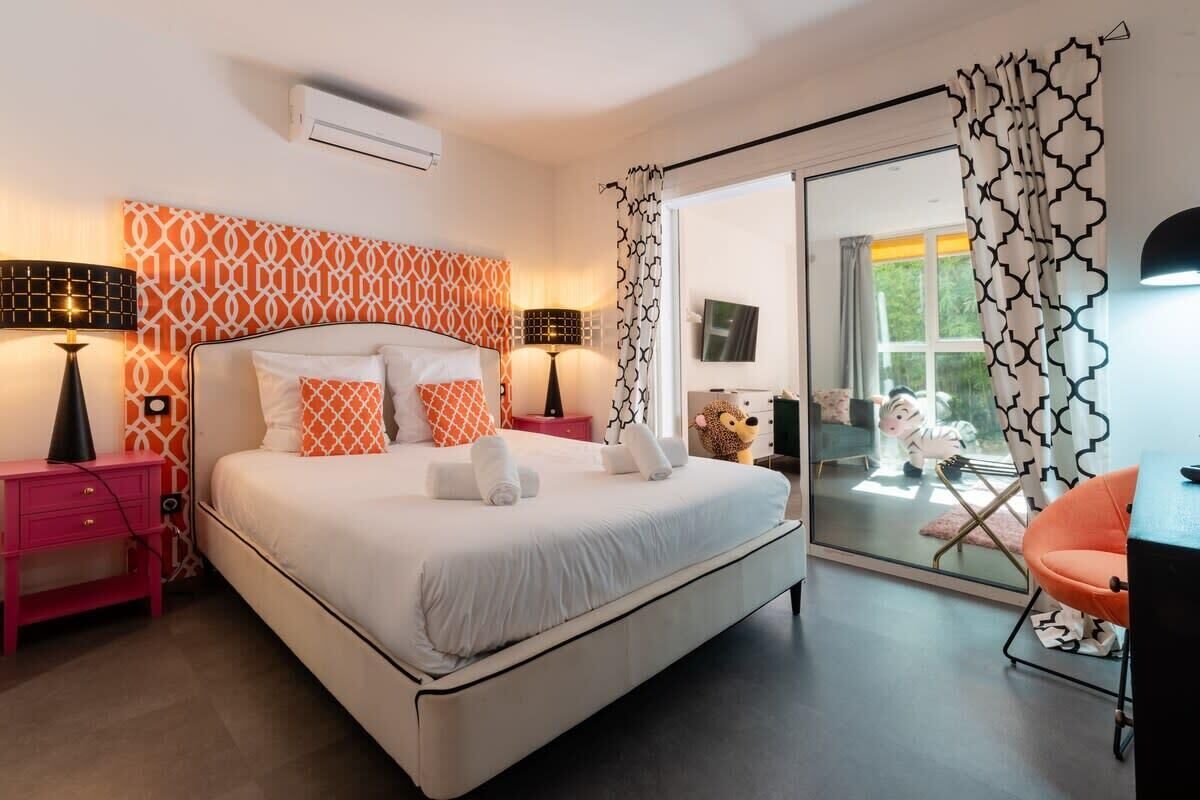 A bedroom with a bed, bedside tables, a chair, and a view through a glass door.