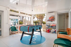 A spacious room with a foosball table, a large window, and a wall with a colorful mural.