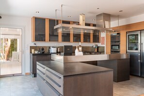 A modern kitchen with a central island, built-in appliances, and a view to the outside.