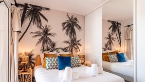A hotel room with a large bed, a mirror, and a wall mural of palm trees. - Villa Summer Wind - Palm Beach Agathois (Agde)