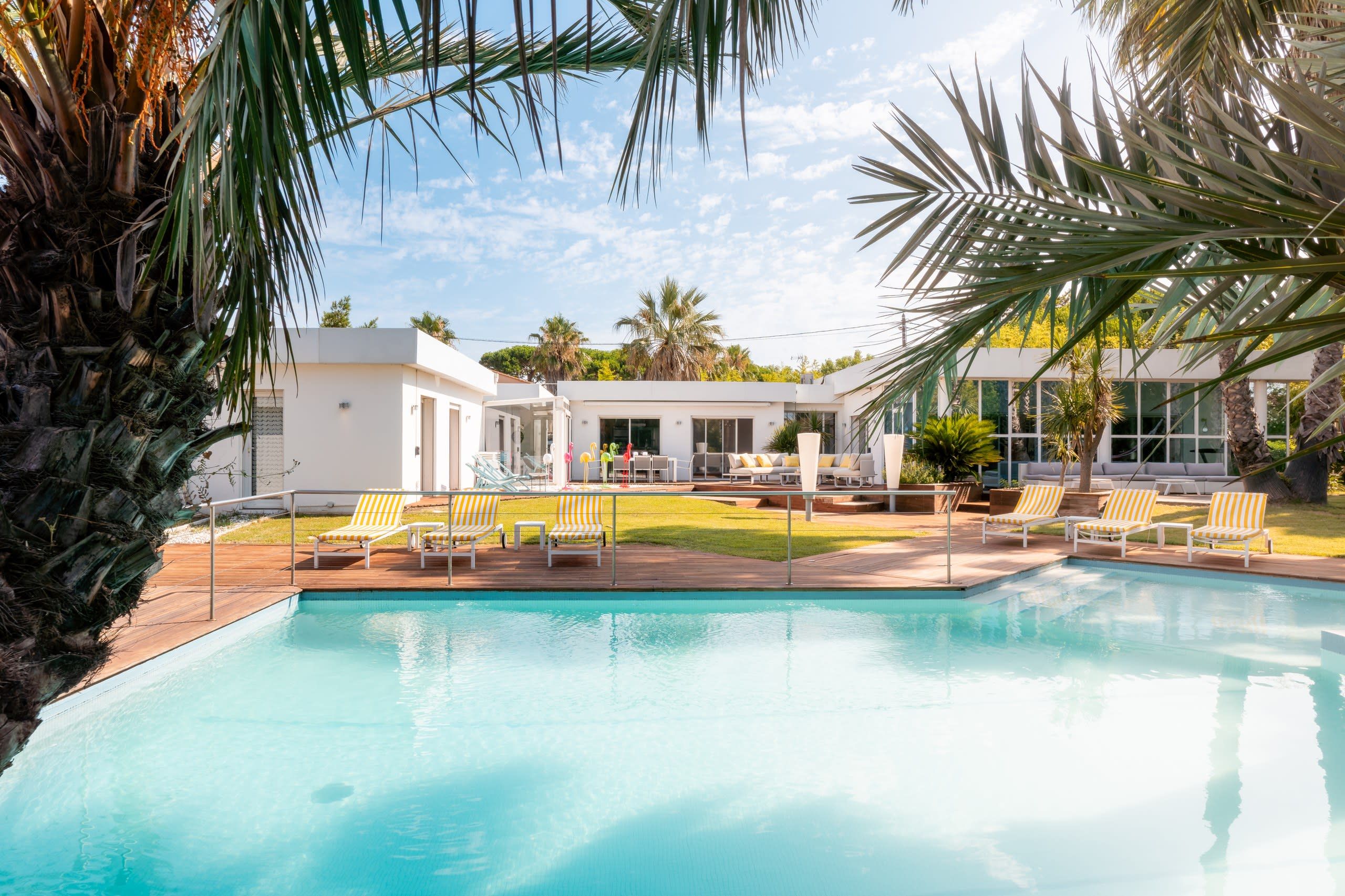 A swimming pool with lounge chairs and a modern building with large windows.