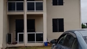 Un edificio de varios pisos con balcones y un coche estacionado en la calle.