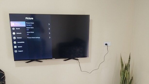 Un televisor de pantalla plana montado en la pared, mostrando un menú en la pantalla.