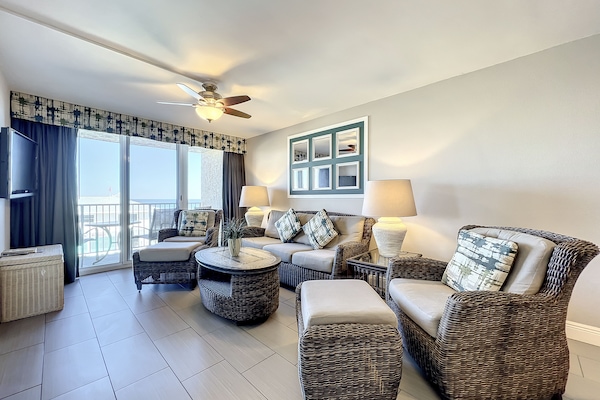 Relax in this modern, sunlit living space with comfortable wicker seating, stylish decor, and expansive ocean views, perfect for a peaceful coastal getaway.