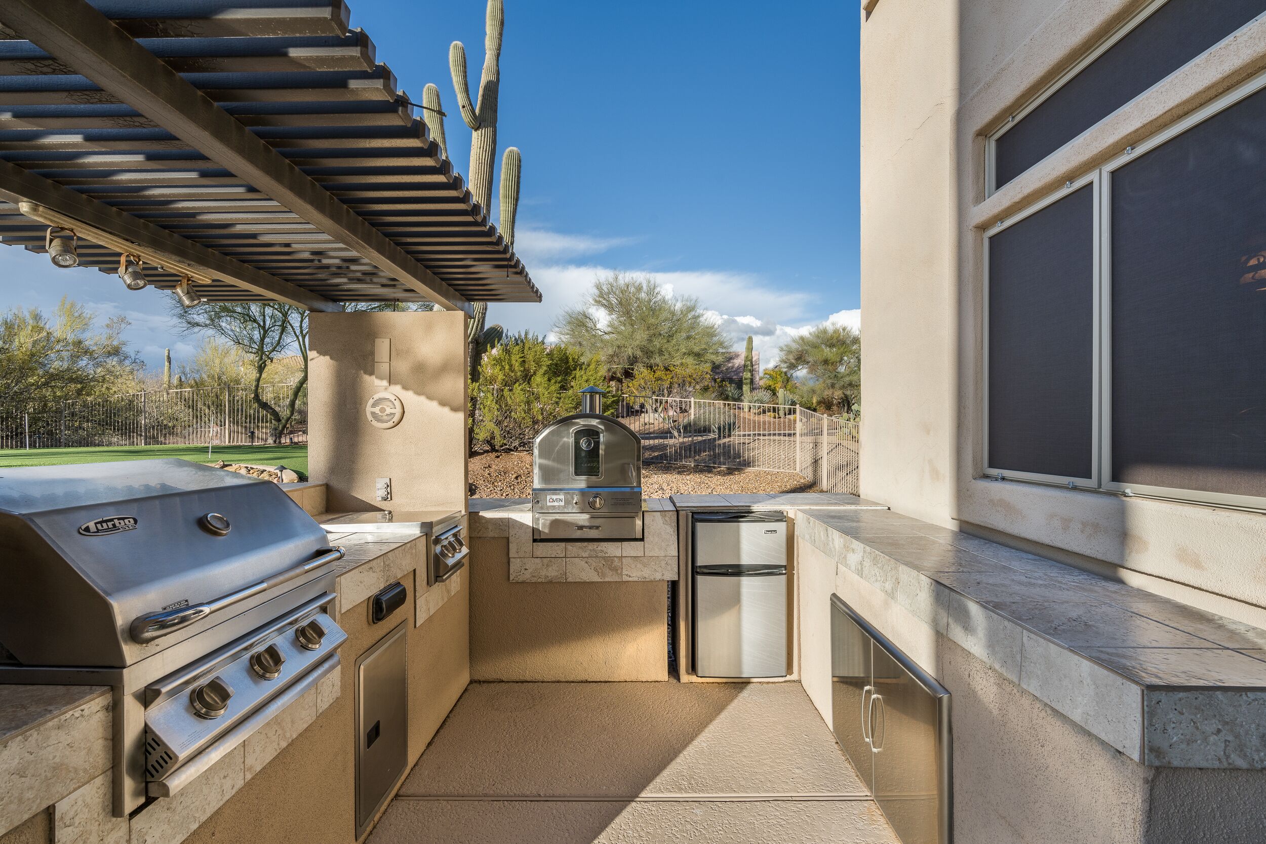 An outdoor kitchen with a grill, a built-in refrigerator, and a chimney.
