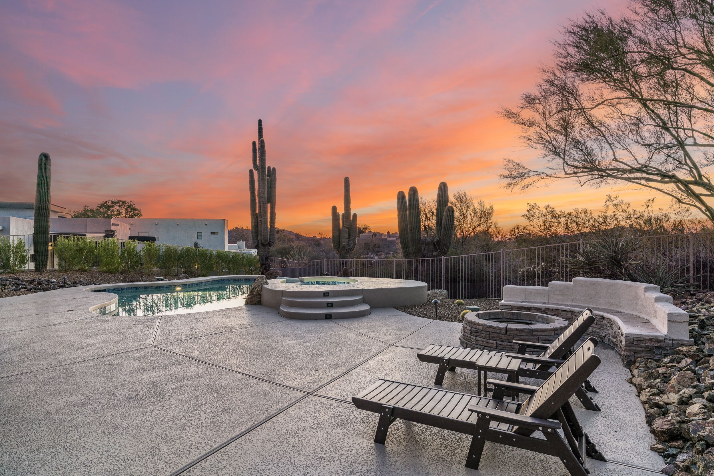 A patio with a pool, lounge chairs, and a hot tub.