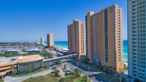 A high-rise hotel with multiple floors, a beach view, and a parking area.