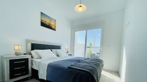 A bedroom with a bed, bedside tables, a nightstand, a window, and a view of the outdoors. - Villa Tranquilidad (Avileses) (Avileses)
