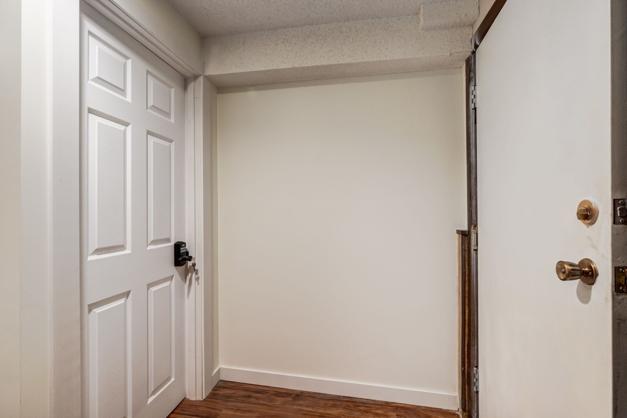 A hallway with a white door on the left and a door with a brass handle on the right.