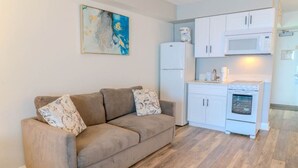 A living room with a beige sofa, a white refrigerator, a microwave, and a stove. - Sea Mist 20407 (Myrtle Beach)