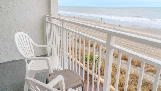 A balcony with white railings overlooking a beach with people in the distance. - Sea Mist 20407 (Myrtle Beach)