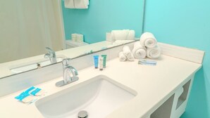 A bathroom with a white sink, a mirror, and toiletries including towels and personal care products. - Sea Mist 20407 (Myrtle Beach)