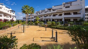 Un edifici modern amb múltiples balcons, una zona exterior ben cuidada amb equipament esportiu i vegetació exuberant.