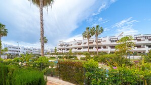 A modern hotel with multiple floors, a swimming pool, and lush greenery.
