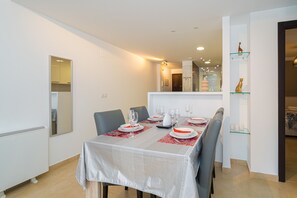 A dining area with a table set for four, chairs, and a mirror on the wall. - Apartamento Mariphils (Linnea Sol) (Orihuela Costa)